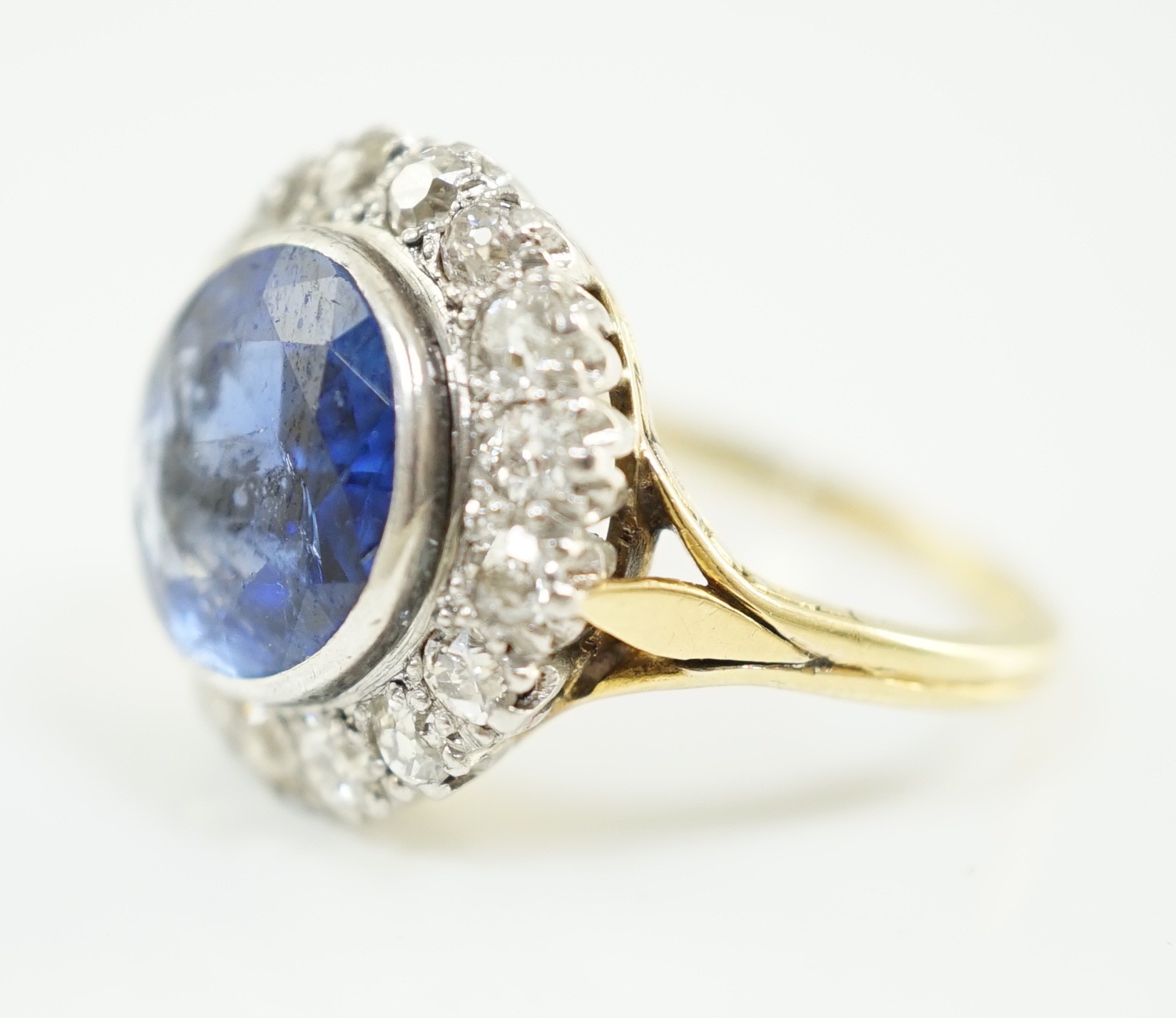 A gold and single stone round cut sapphire set dress ring, with diamond set border